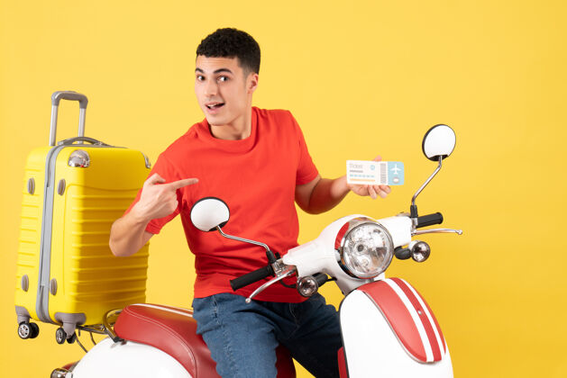 指向正面图：一个穿着红色t恤的年轻人坐在轻便摩托车上指着车票成人视图男