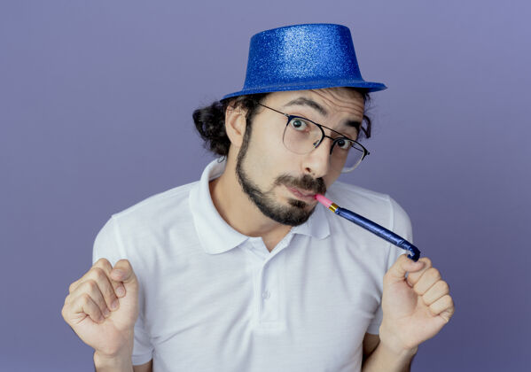 手势高兴的帅哥戴着眼镜 戴着蓝帽子吹着口哨 摆出“是”的手势帽子表演哨子