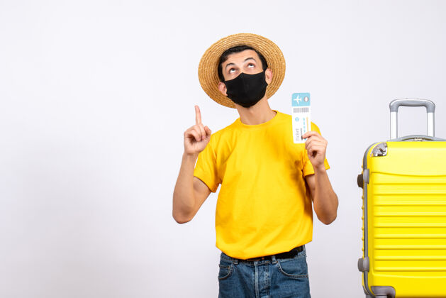 人正面图：戴草帽的年轻人站在黄色手提箱旁 手里拿着机票抱着黄色前面
