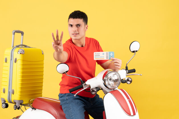 轻便摩托车前视图：坐在轻便摩托车上的年轻人拿着车票 伸出三根手指景手指车