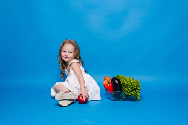 可爱蓝色墙上挂着蔬菜的小女孩蔬菜女孩蔬菜