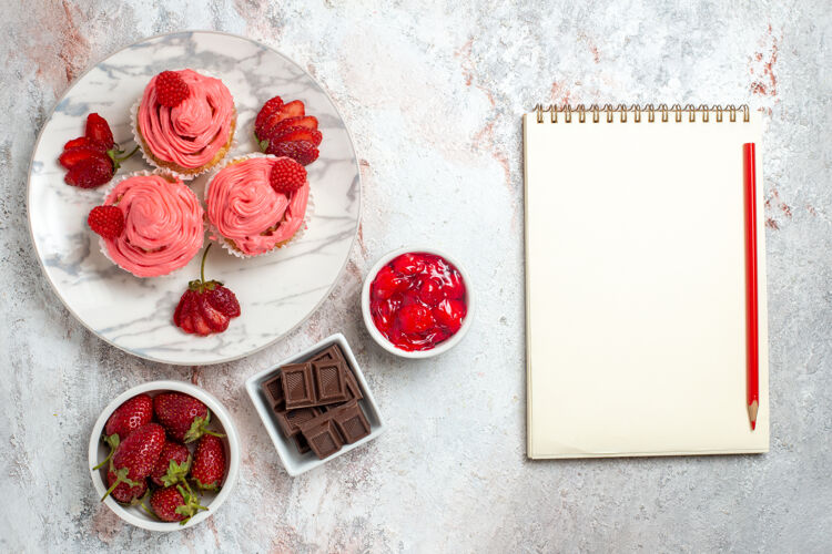 玫瑰白色表面有果酱和巧克力棒的粉色草莓蛋糕俯视图茶饼干果酱