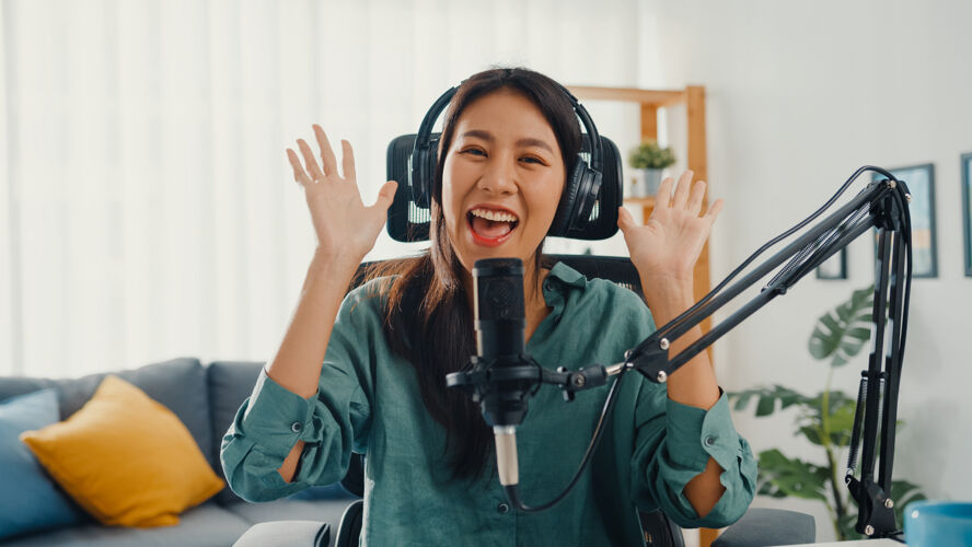 耳机快乐的亚洲女孩用耳机和麦克风录制播客名人记者博客