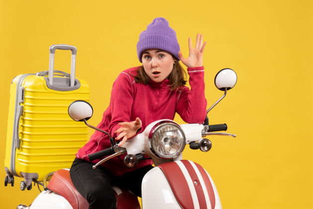坐着前视图可爱的小女孩 戴着紫色帽子 骑着轻便摩托车快乐成人帽子