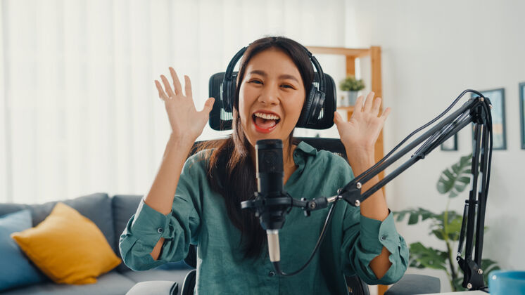 耳机快乐的亚洲女孩用耳机和麦克风录制播客名人记者博客