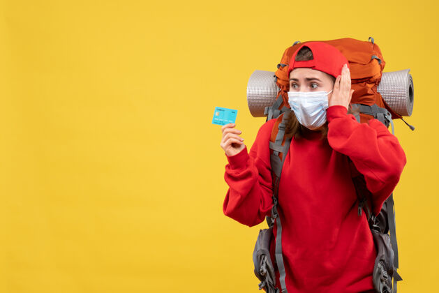 正面前视图困惑的女徒步旅行者背包和面具持有信用卡面具背包信用
