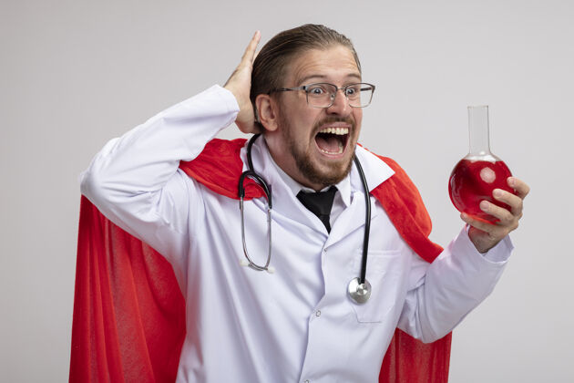 害怕一个年轻的超级英雄 穿着医用长袍 戴着听诊器和眼镜 手里拿着一个装满红色液体的化学玻璃瓶 手放在头上 和白色隔离红色医疗家伙