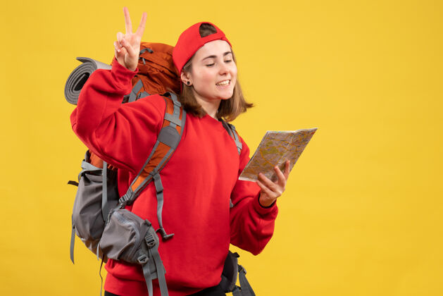 背包正面图漂亮的女旅行者背着背包拿着地图示意胜利标志帽子快乐前面