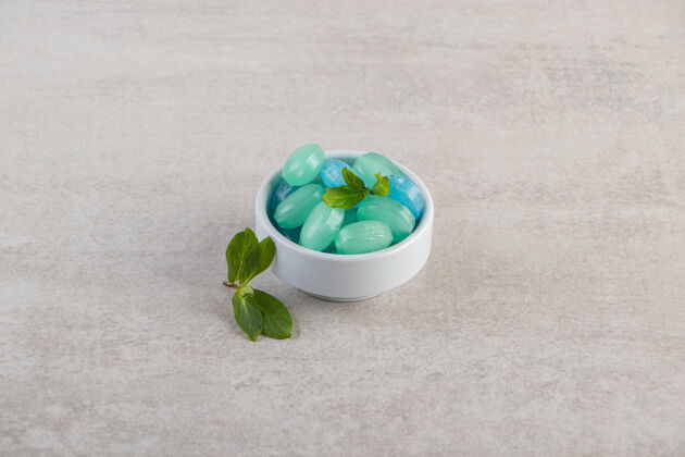 糖果蓝色和绿色的硬糖在碗里放在石桌上蓝色美味绿色