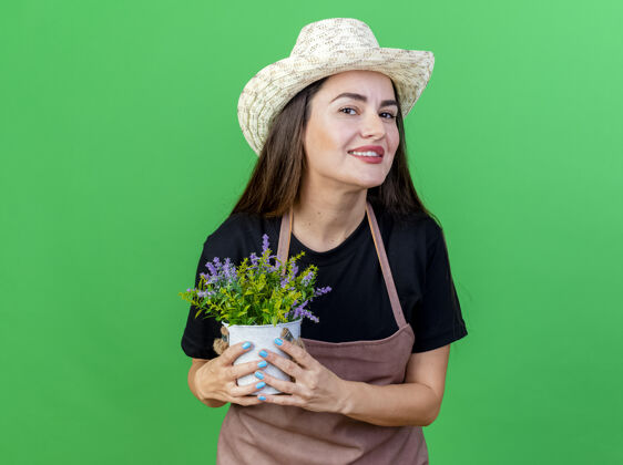 绿色微笑美丽的园丁女孩穿着制服 戴着园艺帽 捧着花盆里的花 孤零零地站在绿茵场上花园园艺帽子
