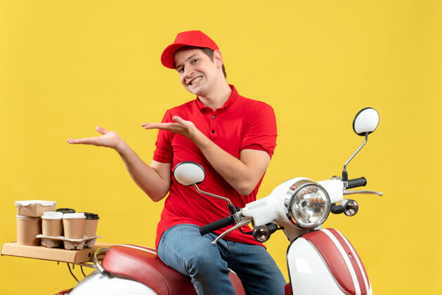 右正面是一个微笑的年轻人 穿着红色上衣 戴着帽子 在黄色的背景下 他指着右边的东西 下达命令摩托车车辆微笑