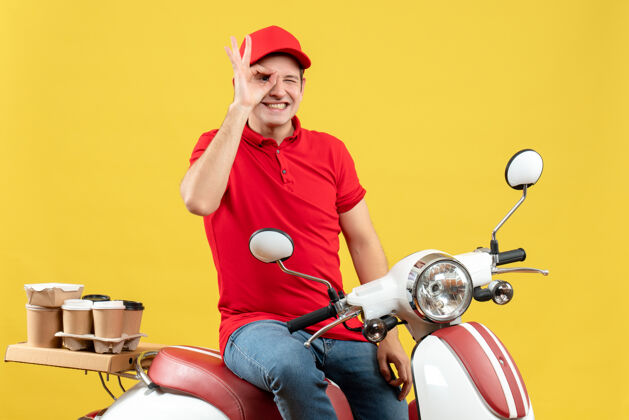 年轻人顶视图的快乐年轻人穿着红色衬衫和帽子传递命令 使黄色背景上的眼气手势制造帽子车辆