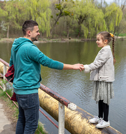 男人早春的时候 爸爸和女儿在森林里散步 互相对视 手牵着手欢呼父母湖泊