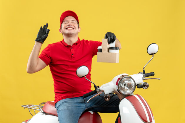 交付正面图微笑的快递员身穿红色上衣 戴着帽子手套 戴着医用面罩 坐在滑板车上拿着订单男子帽子摩托车