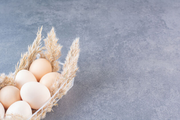 新鲜石桌上放着新鲜生的白鸡蛋和麦穗蛋食物白