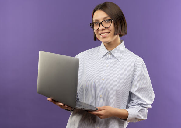表情微笑的年轻呼叫中心女孩戴着眼镜拿着笔记本电脑隔离在紫色的墙上人中心眼镜