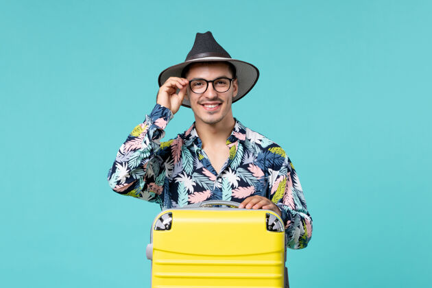 微笑年轻男子背着他的黄色袋子在蓝色的墙上微笑着准备旅行旅行前面工人