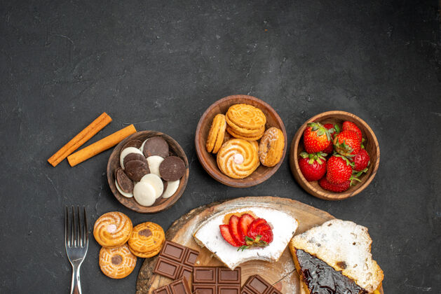 水果在黑色背景上俯瞰蛋糕片和饼干和巧克力美味硬币巧克力