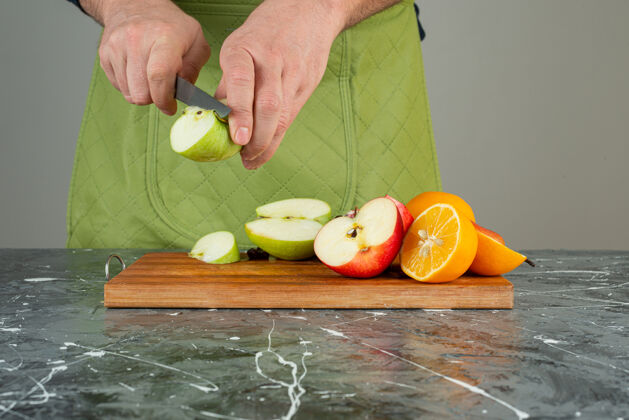 苹果男手切新鲜苹果放在桌上的木板上手切手套