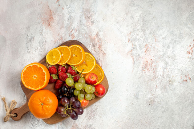 食品白色表面上的新鲜水果成分橙子葡萄和草莓的俯视图成熟水果新鲜