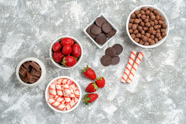 糖果在灰白色的地面上放着糖果草莓巧克力谷类糖果和一些草莓糖果巧克力的顶视图碗草莓美食小吃