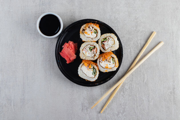美味传统的寿司卷在黑色盘子上装饰着脆片米饭寿司鱼