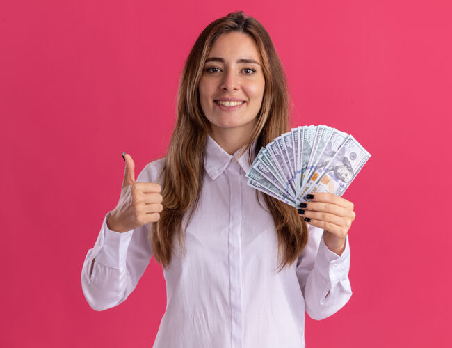 漂亮年轻漂亮的白人女孩微笑着竖起大拇指 手里拿着粉红色的钞票年轻钱模特