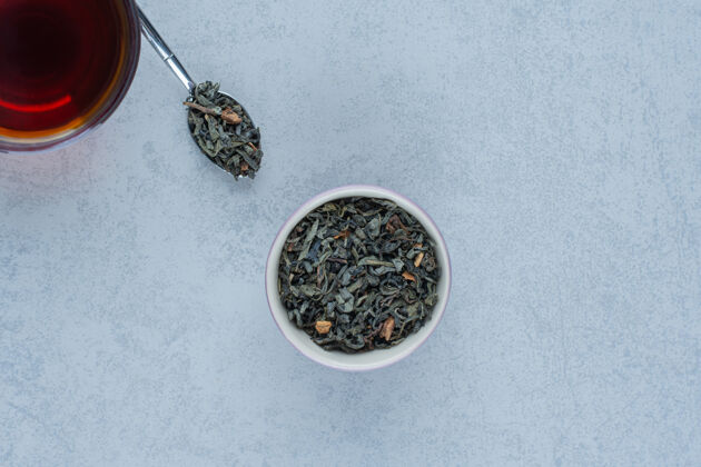 可口一碗干茶叶和一杯用勺子放在大理石上的茶叶子风味勺子