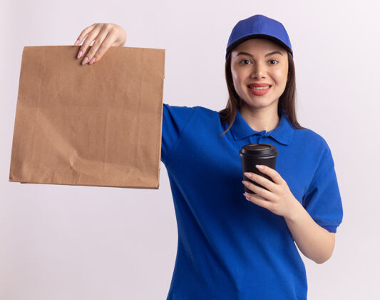 女人一个穿着制服 面带微笑的漂亮女送货员拿着纸包和纸杯看着白色的相机包装漂亮白色