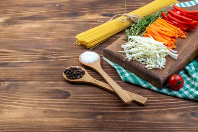 木勺前视图切菜卷心菜胡萝卜青菜和胡椒切菜板棕色表面切片蔬菜切的胡萝卜