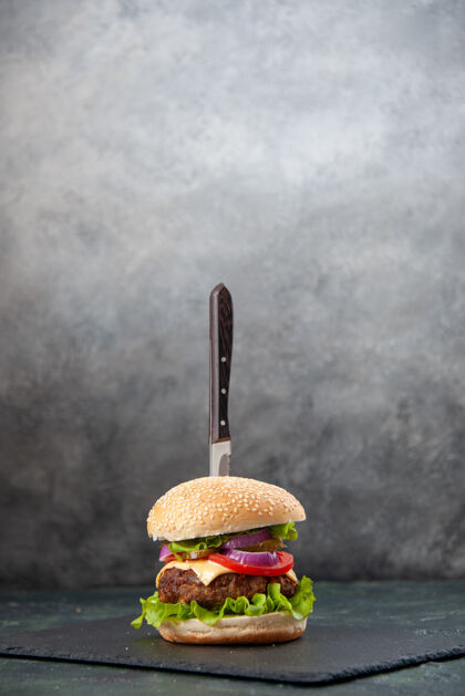刀在孤立的模糊灰色表面上的黑色托盘上美味三明治刀的垂直视图庆祝模糊蛋糕