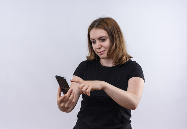 年轻高兴的年轻随意的女人拿着手机 指着它在孤立的空白处复制空间电话手持空间