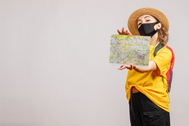 背包前视图可爱的女游客与背包举行地图上的白墙人快乐持有