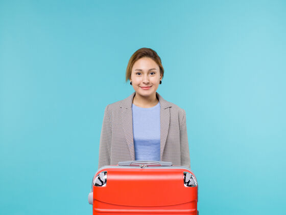 女人前视图女性在度假与她的红色袋子微笑的蓝色背景度假飞机旅行海上旅行旅行前面蓝色