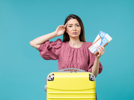 旅程正面图：度假中的女性拿着她的机票在蓝色书桌上旅行 夏季旅行 女性海上度假女人举行成人