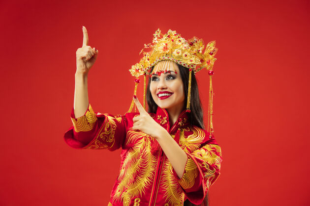 肖像中国传统的优雅女子在摄影棚的红色背景美丽的女孩穿着民族服装中国新年 优雅 优雅 表演者 表演 舞蹈 女演员 服装的概念服装服饰女性