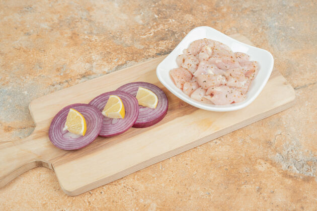 食物在大理石表面用洋葱片和柠檬片做成的木制砧板切片营养饮食