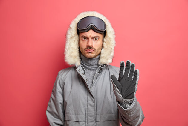 温度严重不高兴的男子滑雪者穿冬衣头戴滑雪镜保持手掌向前作出停止手势外套护目镜男人