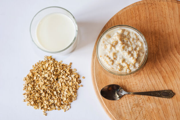 饮食碗里的燕麦片 一杯牛奶 一把勺子和木板上的燕麦片从上面看谷物牛奶素食