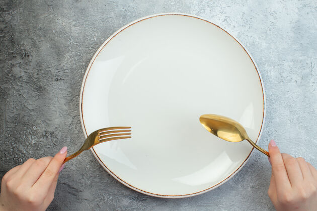 女人女人手里拿着餐具放在灰色的空盘子上碗梯度咖啡