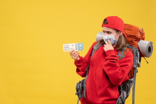 男性前视图困惑的女旅客背包和面具持有机票空气面具人