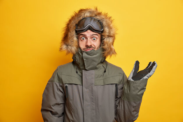 成人穿着冬装的困惑的男人举手 看起来很困惑 在业余时间穿着他的风帽去滑雪白种人人人