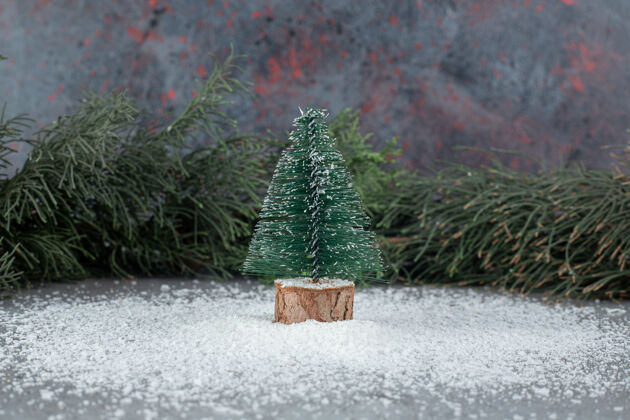 雪小圣诞树雕像旁边的一个常青树枝上的大理石表面树枝节日粉