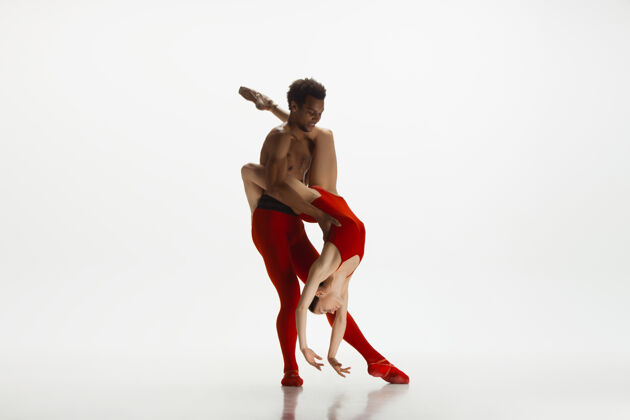 优雅优雅的经典芭蕾舞者在白色的工作室背景上独立地跳舞一对穿着鲜红衣服的舞者就像是酒和牛奶的结合优雅 艺术家 动作 动作的概念艺术家体操织物