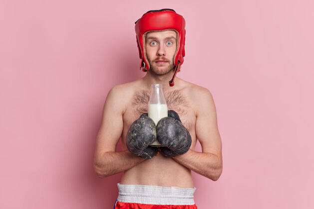 拳击照片中的男拳击手已立志要赢得比赛 备战时戴拳击手套和防护头盔 喝牛奶作为钙源赤膊上阵健身房运动员站立
