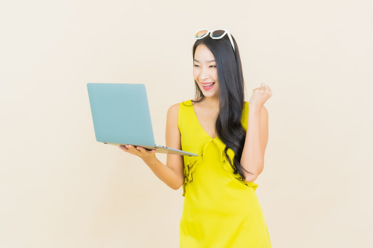 表情一幅美丽的亚洲年轻女子微笑的画像 孤零零的墙上挂着一台笔记本电脑女性乐趣快乐