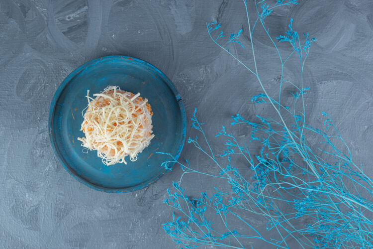 树枝在大理石桌上 蓝色装饰性的树枝旁边放着一盘奶酪盖的米饭烹饪可口美味