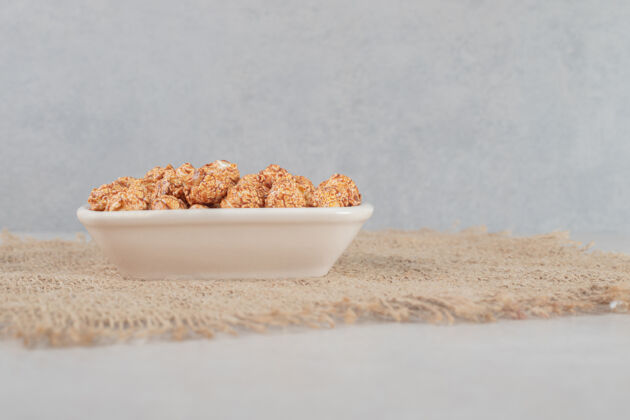 面料在大理石桌上放一块塞满棕色蜜饯爆米花的布碗整理碗可口