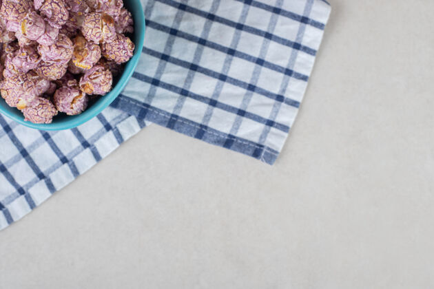 碗蓝色的碗放在折叠的毛巾上 在大理石桌上放满了涂着糖果的爆米花毛巾玉米复制空间