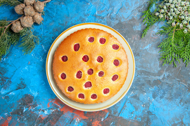 可口蓝色表面上的盘锥上的树莓蛋糕俯视图覆盆子蛋糕培养皿营养